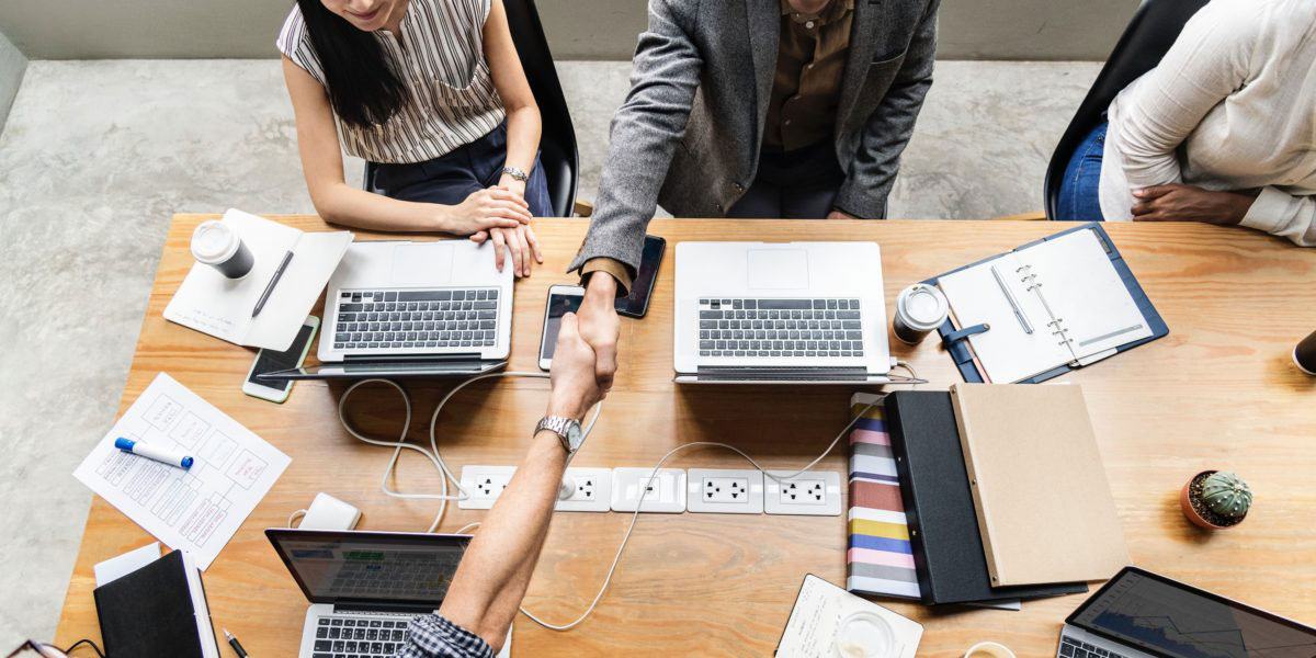 Young professionals collaborate around a table with their laptops
